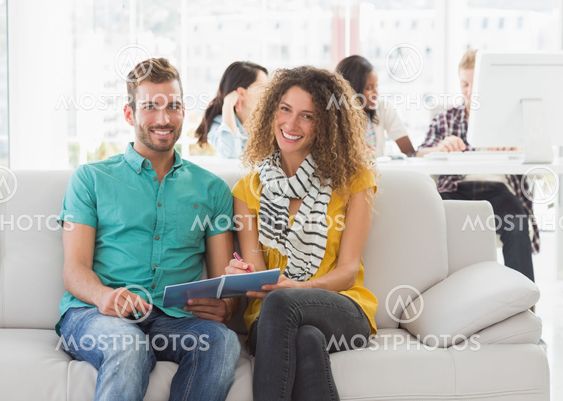 Smiling designers working together on the couch looking at camera