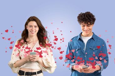 A couple stands together, smiling as they use their...