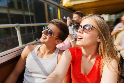 happy teenage couple traveling by tour bus