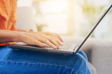 Closeup, woman and laptop with typing on lap for remote...