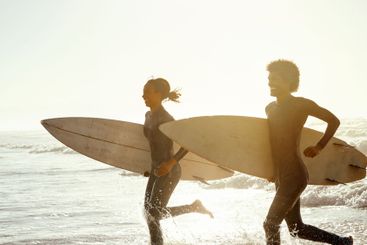 Man, woman and surfing with running at beach for...