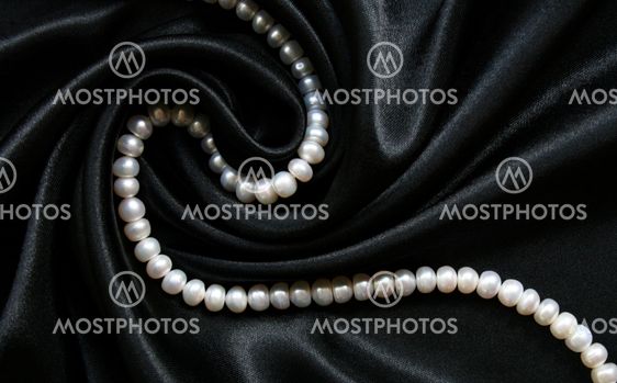 White pearls on the black silk as background
