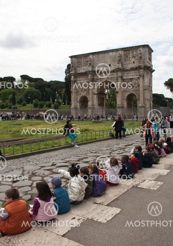 Chlidren sitting near arch of Constantine in Rome, Italy.