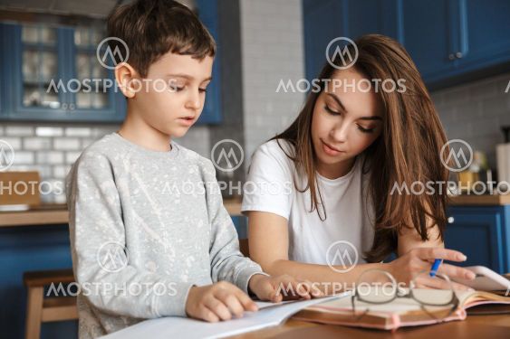 Image of nice woman and cute boy reading exercise while...
