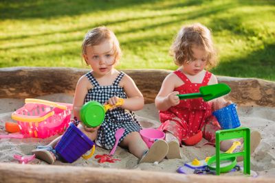The two little baby girls playing toys in sand