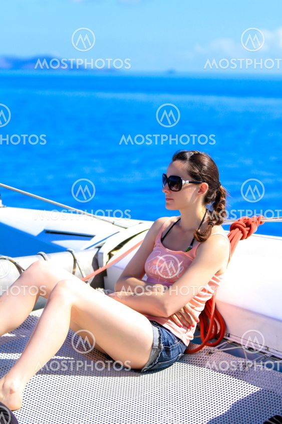 Young caucasian woman sitting in front of a boat