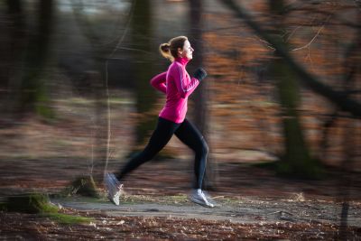 young woman running outdoors in a city park on a cold...