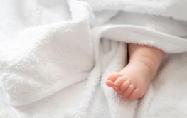 Infant's imprint: baby foot shyly emerging from white...