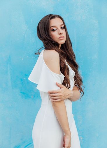 Beautiful Brunette Woman in White Suit on Blue Background