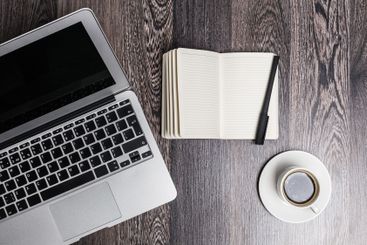 Workspace with laptop, notebook, pen, and coffee cup on...