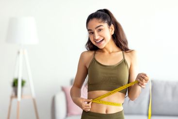 Successful weight loss. Slim Indian woman measuring...