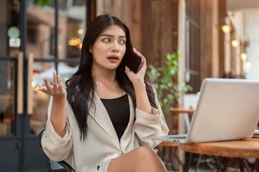 A moody, dissatisfied Asian businesswoman is talking on...