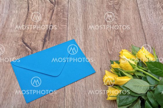 Blue envelope and roses on a wooden background