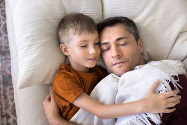 Closeup of father and son sleeping peacefully on white...