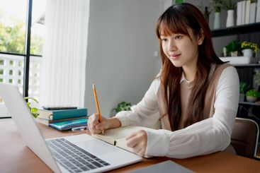 Asian woman using laptop to study student engaged in...