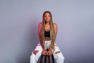 Brunette model with braids in her hair, wearing white...