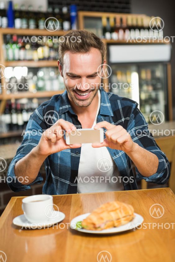 Handsome man taking a picture of his sandwich