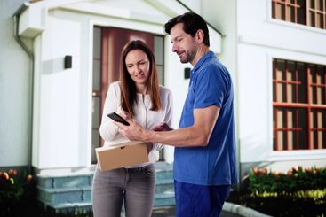 Smiling Delivery Man Handing Parcel to Happy Woman