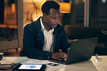African man, technology and typing at night in office...