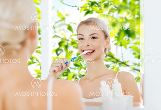 woman with toothbrush cleaning teeth at bathroom