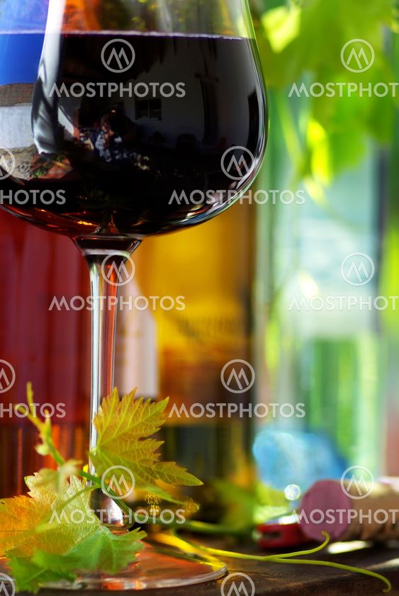 Bottle of red wine with glassand leaves.