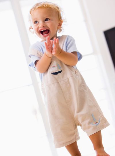 Young boy standing indoors applauding and smiling