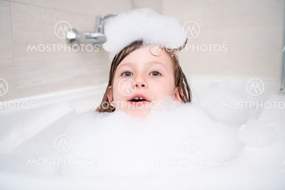 little girl in bath playing with foam
