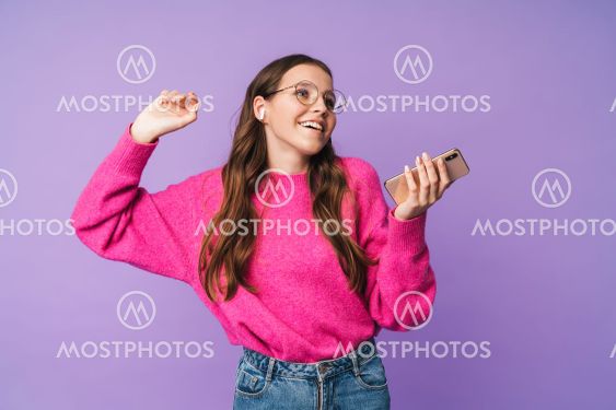 Image of young woman wearing earbuds smiling and holding...