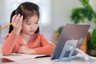 A young girl is concentrating on her homework with a...