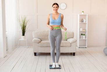 Smiling Girl Measuring Thin Waist Standing On...