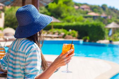 Young woman with cocktail in tropical cafe at exotic resort