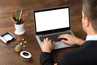 Businessman With Office Supplies Working On Laptop