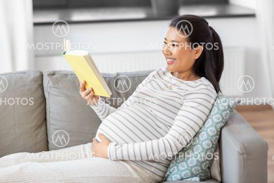 happy pregnant woman reading book at home