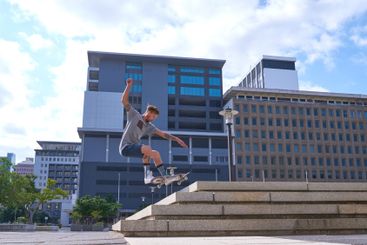Man, skateboard and jump stairs in urban city, ollie and...