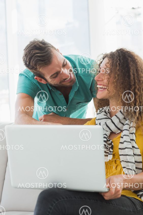 Smiling woman on the couch showing her colleague her laptop