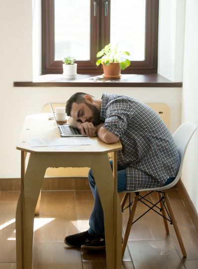 Tired exhausted man with beard sleeping on table in office