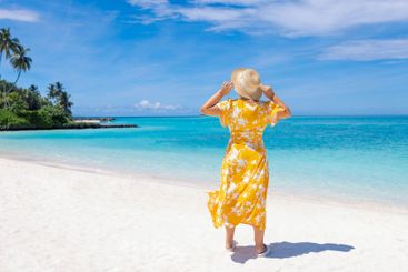A young woman in a light floral print dress and a straw...
