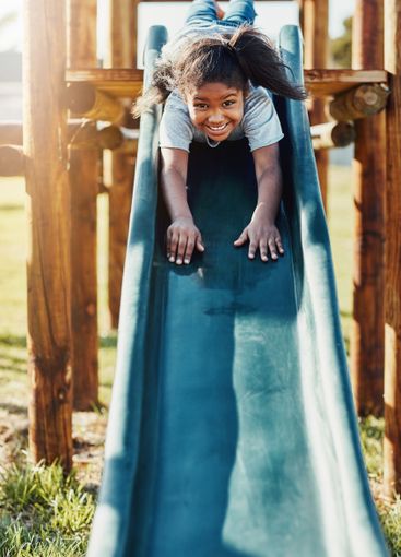 Slide, playing and portrait of kid in park for fun, joy...