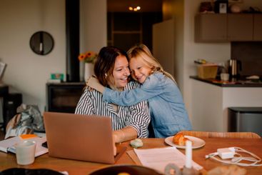 Boy embracing mother working on laptop at home