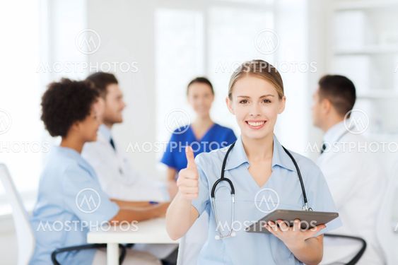 happy doctor with tablet pc over team at clinic