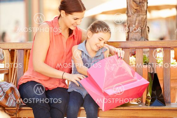 Mother And Daughter Sitting On Seat In Mall Together