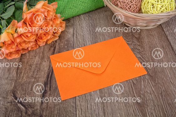 Orange envelope and roses on a wooden background