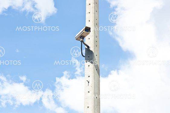 Video surveillance camera attached to electrical pole with blue sky background
