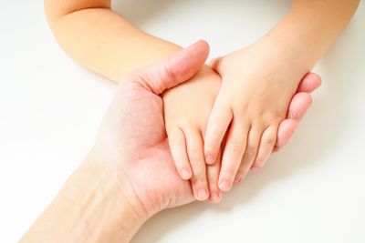 Toddlers hands in fathers hand, towards, on a white table