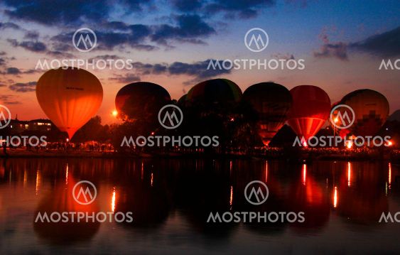 Hot air baloons flying in the evening sky near the lake