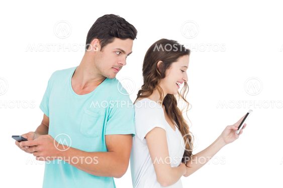 Smiling couple using their smartphones back to back