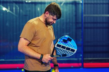 Man engaged in padel preparation indoors while holding a...