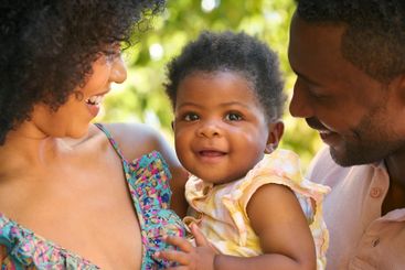 Close Up Of Loving Parents Cuddling Baby Daughter...