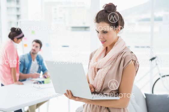 Smiling businessman standing and using laptop