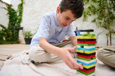 Boy concentrating while building a colorful block tower...
